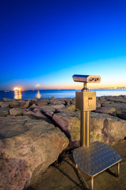 Coin operated binocular on the rocks reverse light image during the sunset