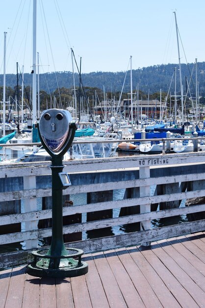 Photo coin-operated binoculars at harbor against clear sky