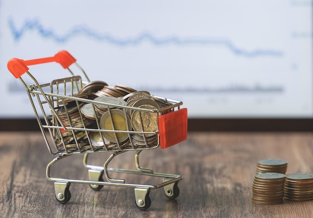 Coin in shopping cart with stock market board 