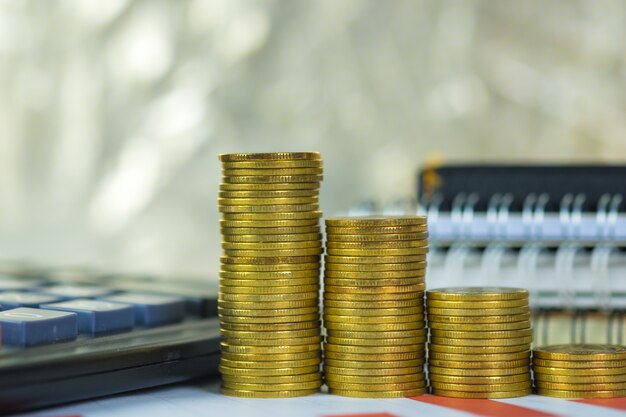 Coin stack and financial graph paper sheet with calculator on working table