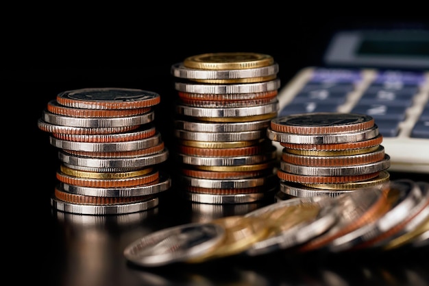 Coin stacks with calculator blurred. Trade, money and financial growth and business concept.