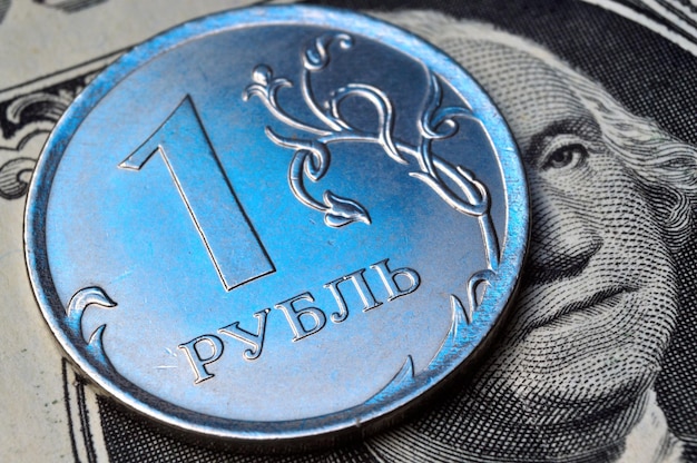 Una moneta con un valore nominale di 1 rublo giace su una banconota del dollaro americano primo piano traduzione dell'iscrizione sulla moneta quot1 rublequot