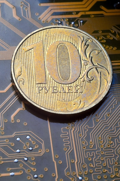 Монета номиналом 10 рублей лежит на микросхеме крупным планом Перевод надписи на монете "10 рублей" Концепция цифровой экономики в РФ