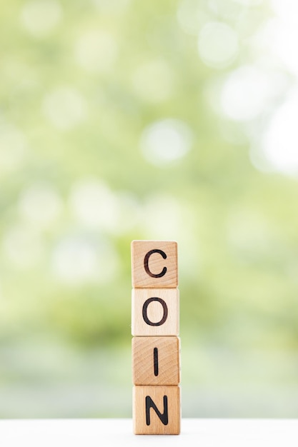 COIN-woord is geschreven op houten kubussen op een groene zomerachtergrond Close-up van houten elementen