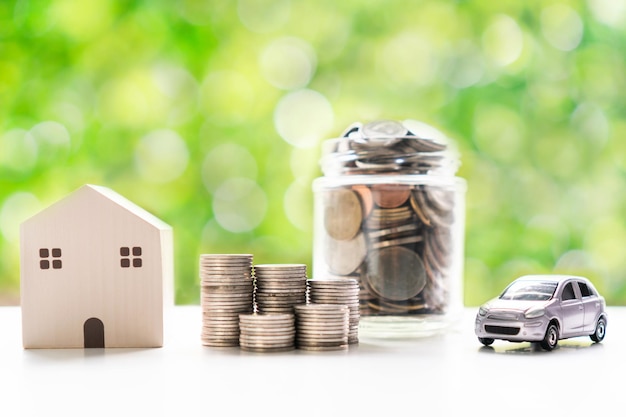 Coins glass jar model home and model car on white table over blur green nature background Saving collect money for future investment concept Close up copy spacex9