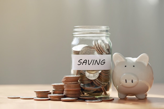 Coins in glass jar and piggy bank on wooden table.money saving financial concept