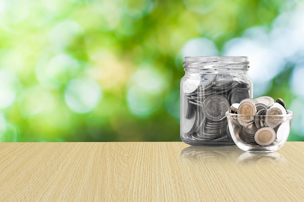 Coins in a glass jar on Wood floor ,savings coins - Investment And Interest Concept saving money concept, growing money on piggy bank. isolated on green background