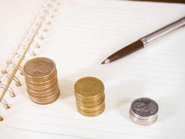 Coins growth with pen on open book