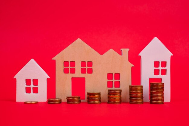 Coins and houses on a red background the concept of the rising\
price of real estate