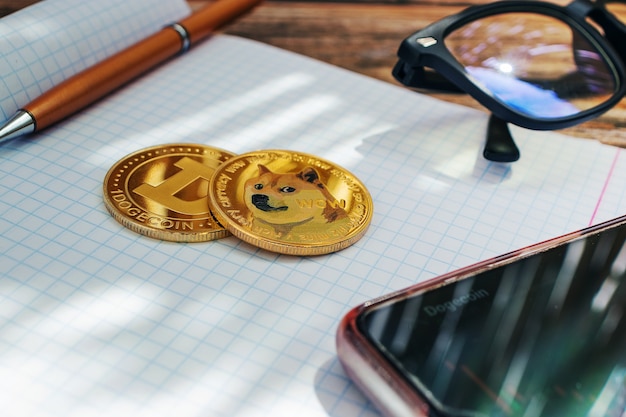 Фото Монеты крупным планом, криптовалюта dogecoin на фоне ноутбука, лучи солнца