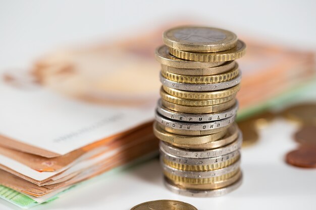 Coins lying on the table with banknotes blurred in the background