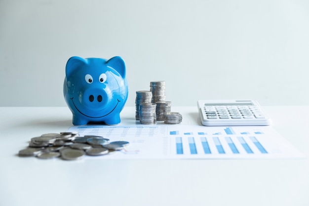 coins pile and blue smiling piggy bank