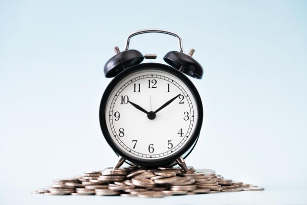 Coins stack and alarm clock on blue background