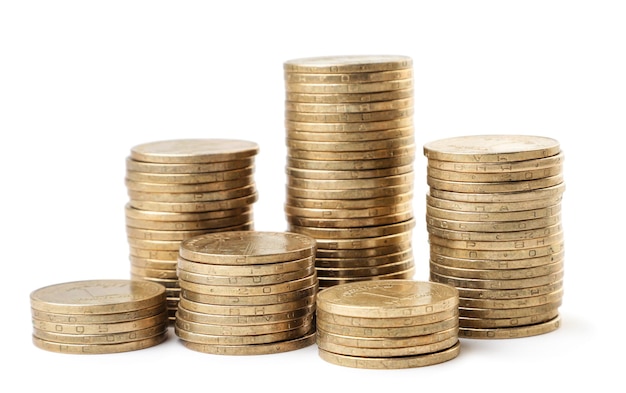 Coins stacked in columns of different heights close-up on a white background. Isolated