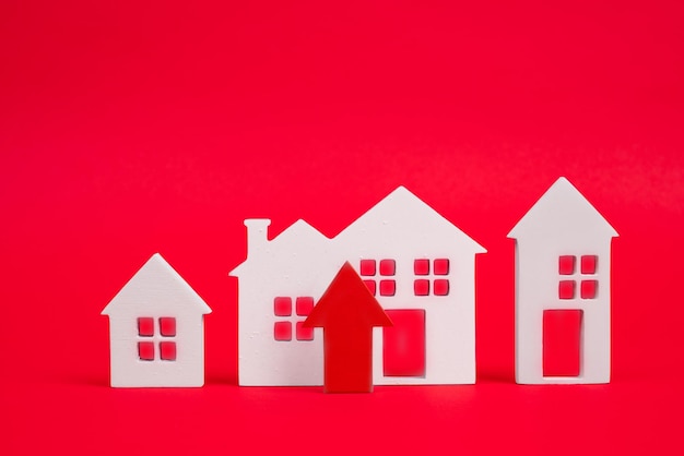 Coins on a table a red up arrow and house The concept of the rising price of real estate