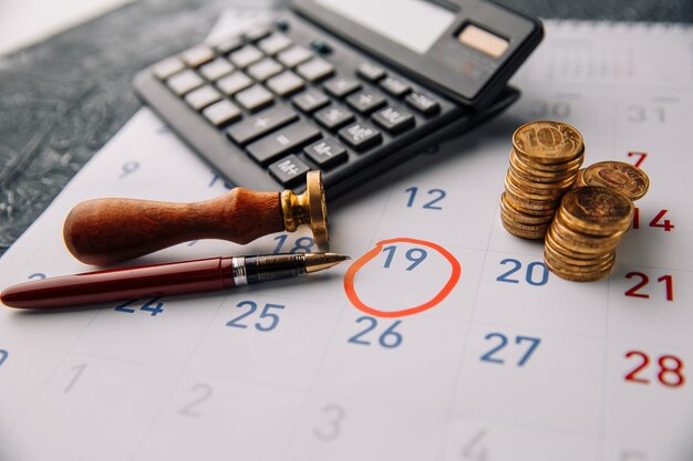 Coins with the calculator on calendar close-up.