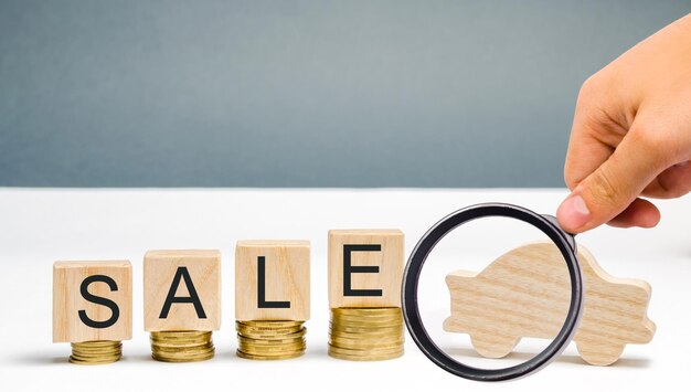 Coins and wooden blocks with the word sale and a miniature car the concept of saving money