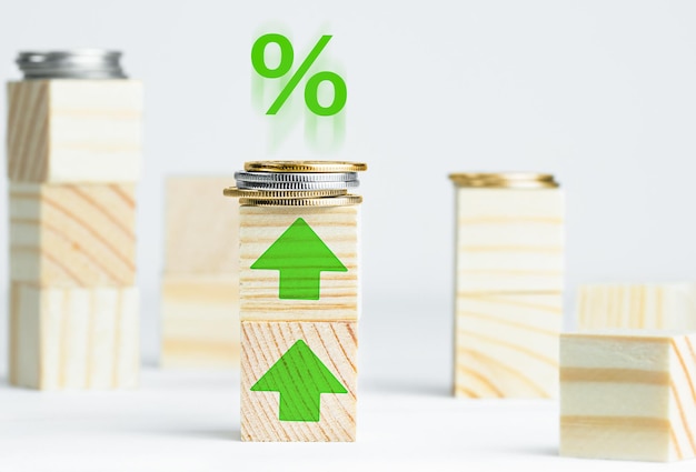 Монеты на деревянных кубических блоках с зелеными стрелками вверх и растущим знаком процента