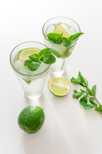 Coktail Gin Tonic of Mojito in glas met munt, ijs, limoen op de witte achtergrond.