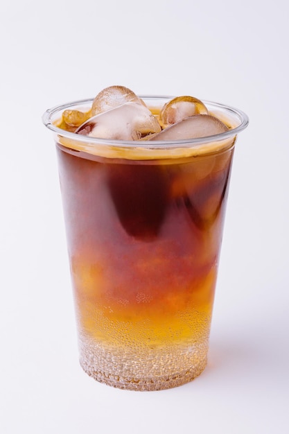 Cola with ice in plastic glass on white background