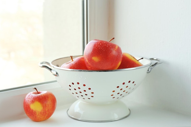 Colander with fresh apples on windowsill