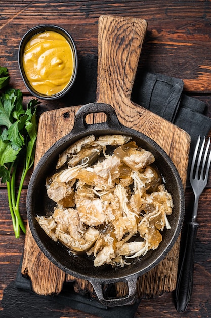 Cold Aspic meat jelly in skillet with mustard. Wooden background. Top view.