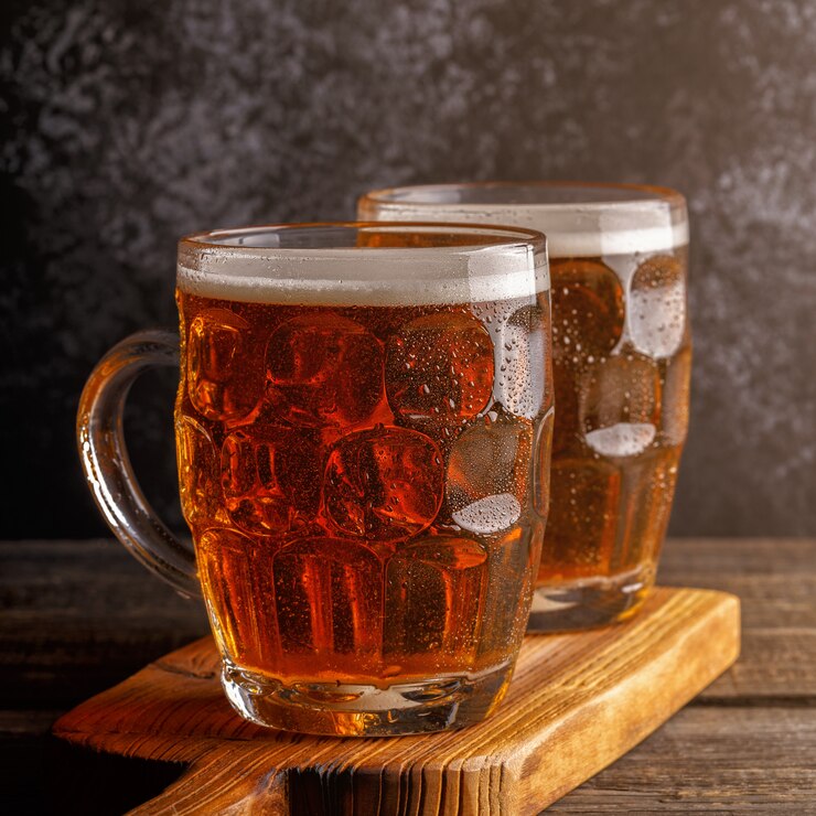 Cold beer in glass pints on a wooden board