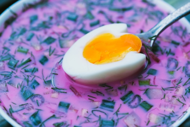 Cold beetroot soup with eggs and bread on a decorative tray