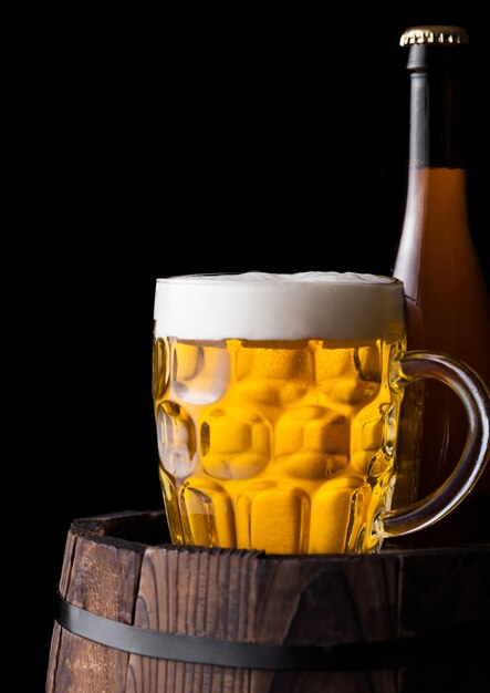 冷たいボトルと黒の背景に古い木製の樽にクラフトビールのグラス