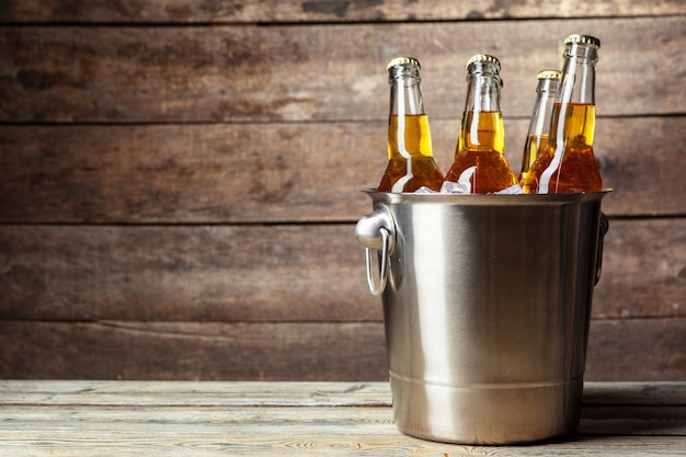 Photo cold bottles of beer in the bucket on wooden