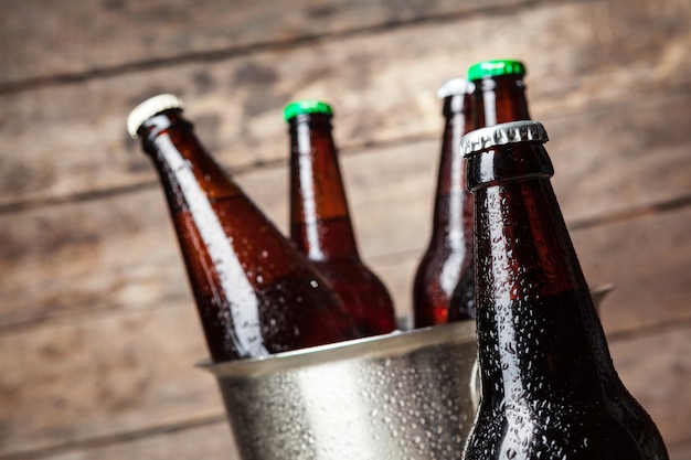 Cold bottles of beer in the bucket on the wooden 