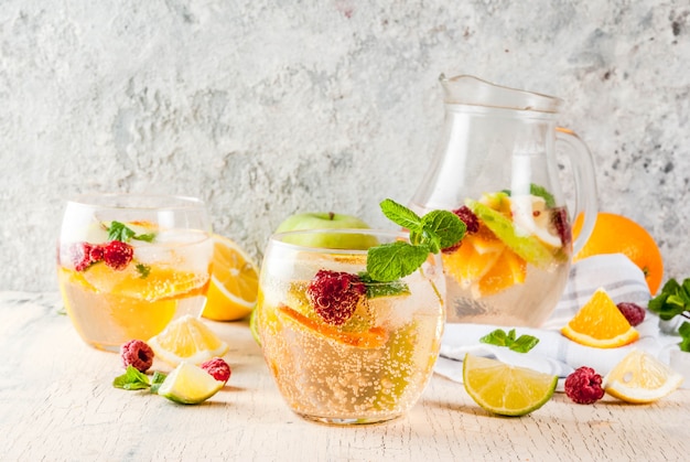  cold cocktail, fruit and berry white sangria with apple, lemon, oranges and raspberry