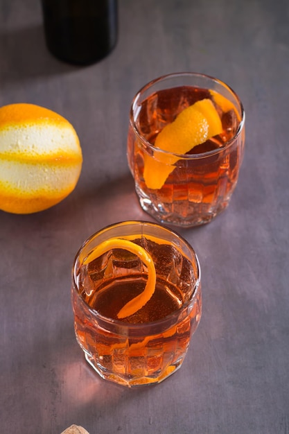 Cold cocktail Negroni Sbagliato with liqueur vermouth and orange in glasses on the table vertical