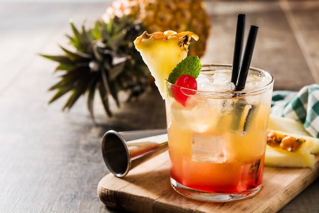 Cold cocktail with pineapple and cherry on wooden table