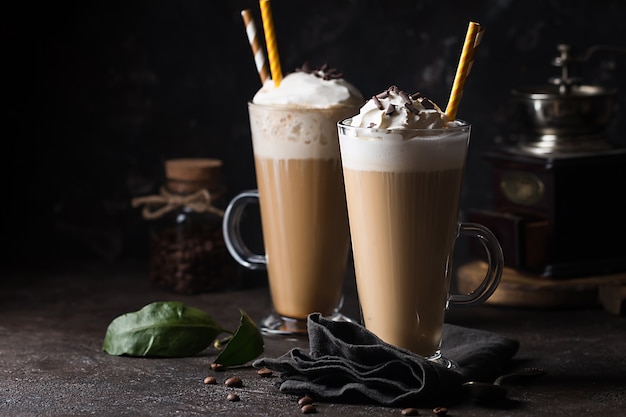 Cold coffee drink frappe or frappuccino, with whipped cream and chocolate chips, with straws over dark surface