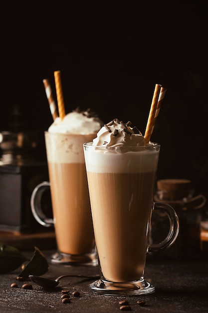 Cold coffee drink frappe or frappuccino, with whipped cream and chocolate chips, with straws over dark surface