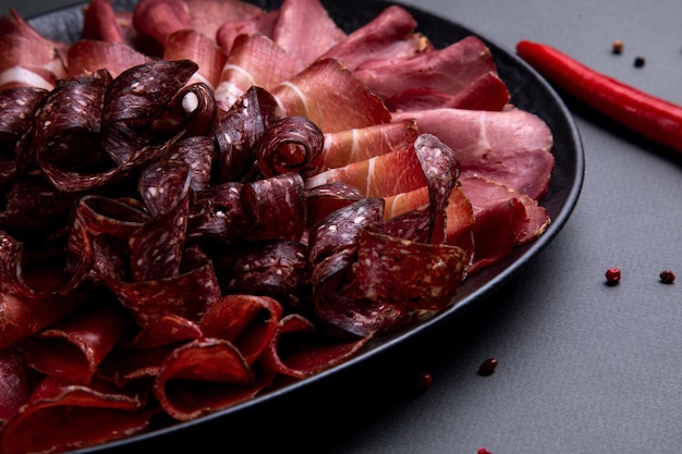 Cold cuts on a black plate on a dark decorated background