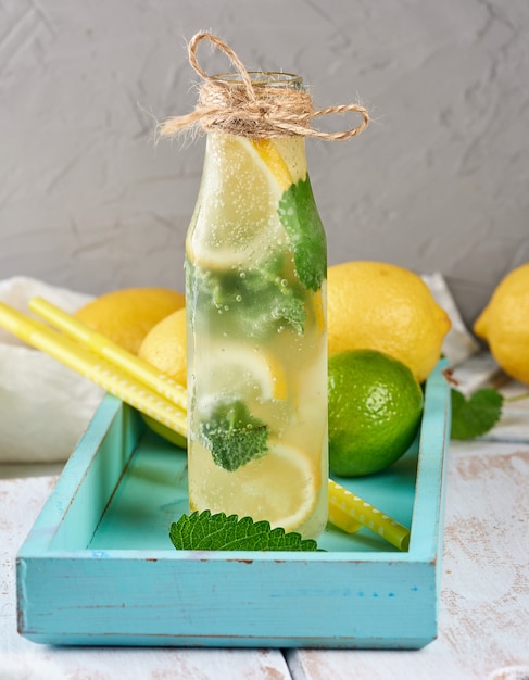 Cold drink with lemons, mint leaves, lime in a glass bottle