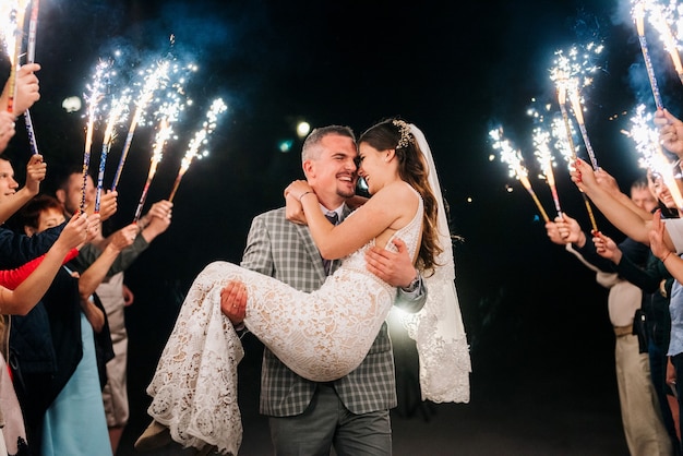 Cold fire from cake candles and fireworks in the hands of people around the newlyweds