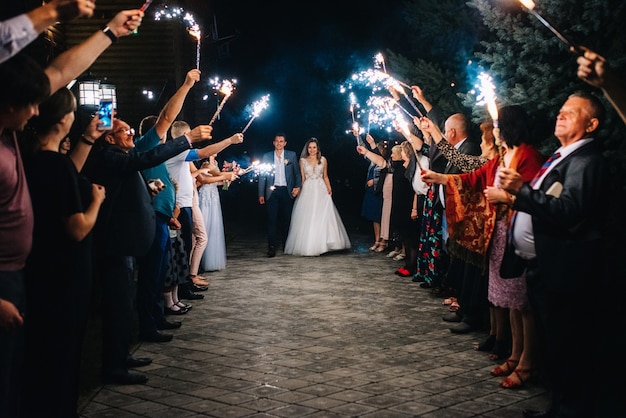 Foto fuoco freddo da candele e fuochi d'artificio nelle mani delle persone intorno agli sposi