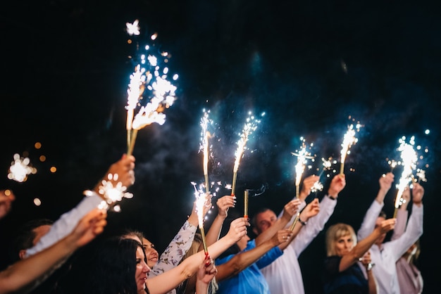 Cold fire from cake candles and fireworks in the hands of people around the newlyweds