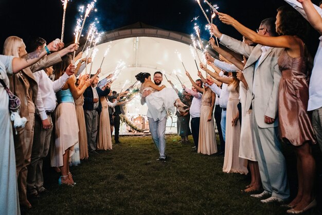 Cold fire from cake candles and fireworks in the hands of people around the newlyweds