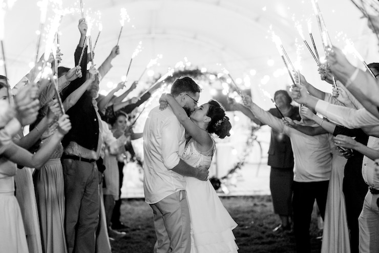 Photo cold fire from cake candles and fireworks in the hands of people around the newlyweds