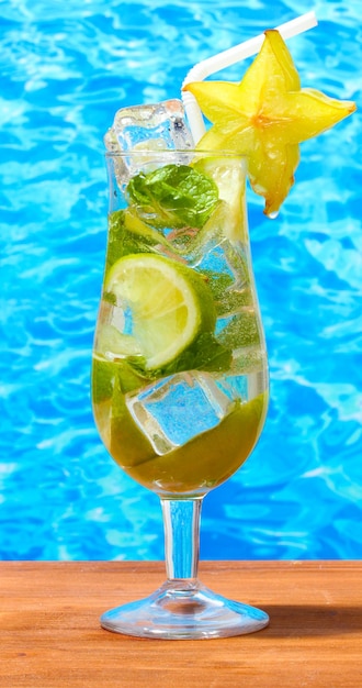 Cold fresh lemonade on wooden table on sea background