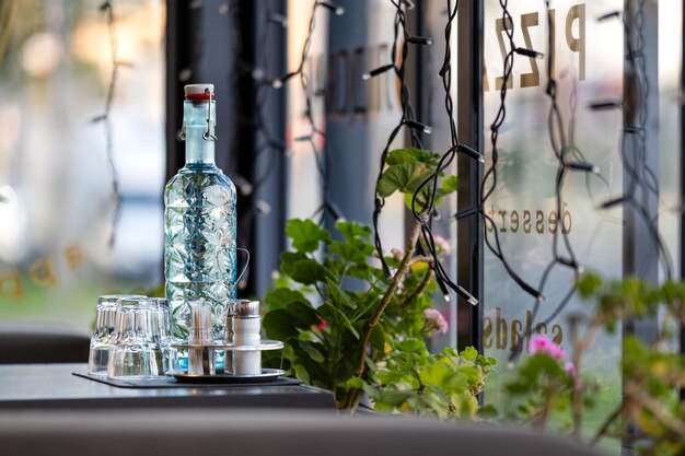 Cold fresh water in oldfashioned bottle with glasses on a cafe table