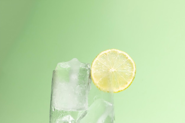 Cold glass full of ice with a lime ready to serve light green with cast shadow