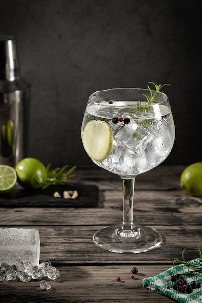 Foto bicchiere freddo di gin tonic con ghiaccio su fondo rustico scuro con spazio per la copia formato verticale