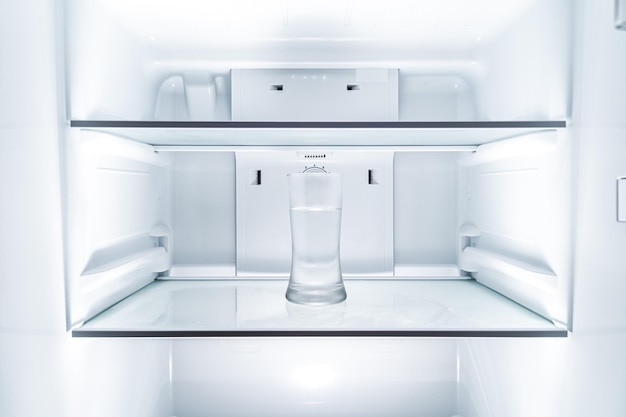 Photo cold glass of water in clean refridgerator