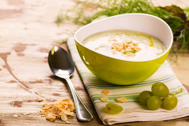 Cold green gaspacho soup with grapes, almonds and dill on grunge wooden rustic background