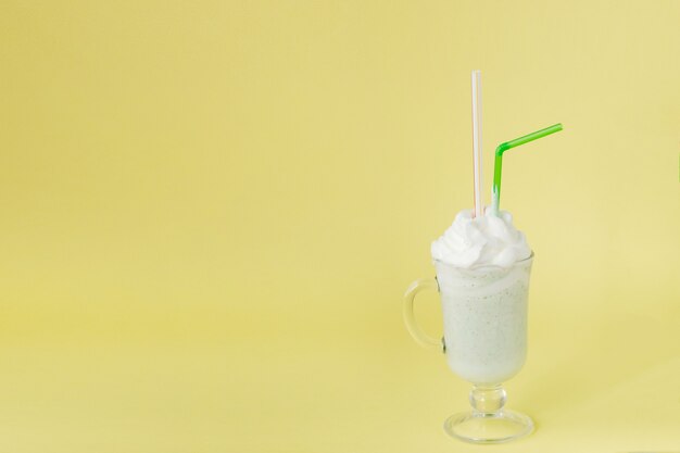 Cold green peppermint milkshake on a yellow wall